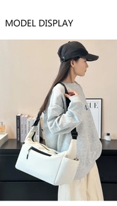 Borsa a tracolla in nylon bianco con tasche laterali e tracolla nera indossata dal modello