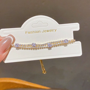 Detail of adjustable gold-plated bracelet featuring square purple stones and double-row zircon
