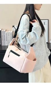 Dettaglio borsa a tracolla in nylon rosa con tasca laterale e tracolla regolabile sul modello