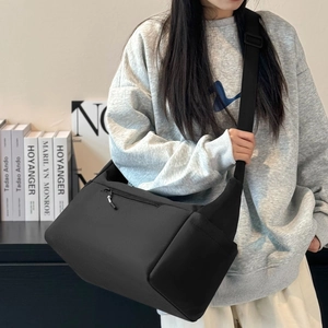 Grande borsa a tracolla in nylon nero con ampia cinghia indossata dal modello