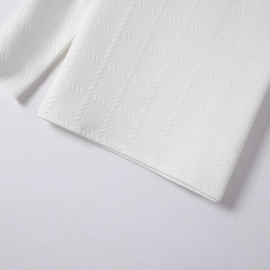 Macro d'un polo blanc montrant la texture jacquard tissée et les motifs chevrons