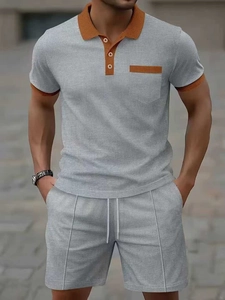 Detailed close-up of waffle knit texture and contrast orange trim on light grey men polo set