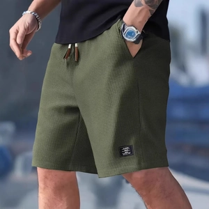 Detail of army green waffle knit fabric texture and logo patch on men's casual shorts