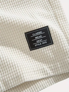 Detail showing white waffle texture fabric with square classic wear logo patch and stitching