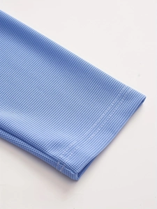 Detailed macro view of light blue waffle knit fabric and double-stitched sleeve cuff seam