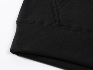 Detail of high-density cotton hoodie ribbed hem and pocket stitching on black sweatshirt