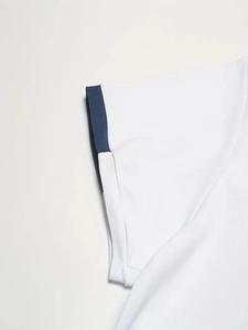 Dettaglio della manica della polo bianca in cotone piqué con bordo a coste blu navy