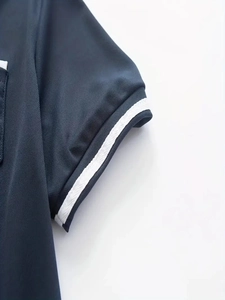 Close-up of navy polo shirt sleeve featuring white knitted trim and breathable fabric texture