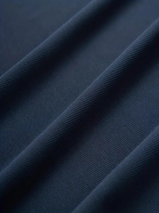 Macro texture of navy blue mesh fabric showing breathable knit detail for polo shirts