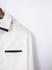 Detail of white cotton slim fit shirt featuring black contrast piping on collar and pocket