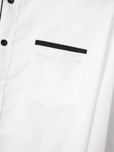 Detail of white cotton shirt showing pocket with black piping and contrast buttons