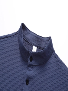Detail des marineblauen Polo-Kragens mit Waffelstruktur und schwarzen Knöpfen