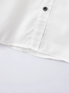 Detail of white cotton shirt featuring a black four-hole button and precise stitching