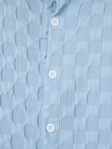 Detailed close-up of light blue shirt with seersucker checkerboard texture and white buttons