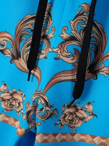 Detail der blauen Herren-Strandshorts mit goldenem Barock-Blumendruck und Kordelzug