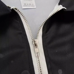 Close-up of a men's black polo shirt with white zipper detail and 100% polyester fabric label