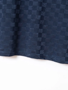 Macro detail of navy blue checkerboard knit fabric and reinforced hem stitching