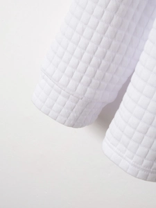 Vue détaillée de la texture gaufrée blanche et des poignets côtelés de ce polo décontracté