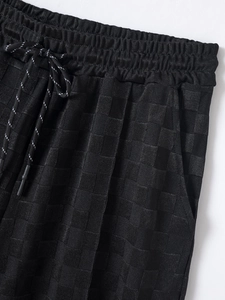 Detail view of black checkerboard texture on men's ice silk shorts with elastic drawstring waist