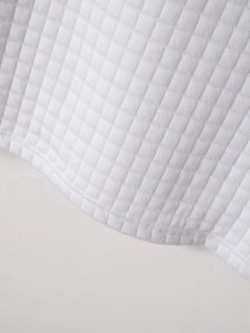 Détail du tissu matelassé blanc à carreaux et de la couture double sur l'ourlet du polo