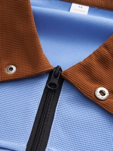 Dettaglio del colletto con zip a contrasto su polo in maglia nido d'ape blu e marrone