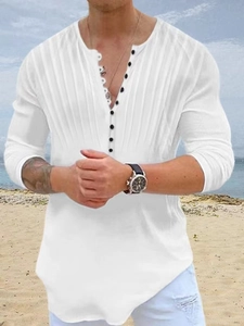 Detail of white Henley shirt with black buttons and vertical pleated texture on beach