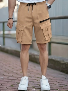 Detail of khaki cargo shorts featuring large flap pockets and adjustable drawstring waist