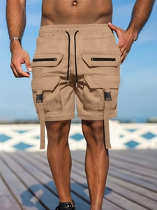Detail of khaki cargo shorts featuring multiple zip pockets and adjustable drawstring waist