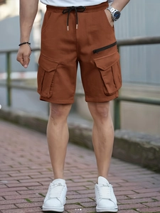 Detail of men's cargo shorts with elastic waist and metal-tipped drawstring in ochre
