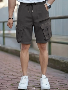 Detail of dark grey cargo shorts featuring elastic drawstring waist and large utility pockets