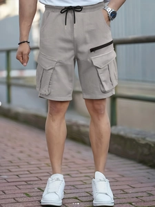 Detail of light khaki cargo shorts featuring functional flap pockets and elastic drawstring waist
