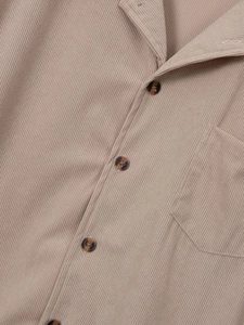 Detail of khaki ribbed shirt featuring tortoiseshell buttons and a chest pocket