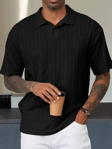 Détail du polo en maille noire avec texture en losanges et finitions côtelées premium