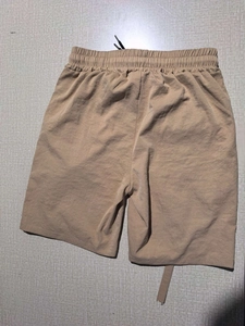 Flat lay of khaki men's casual shorts with elastic waistband and black drawstring detail