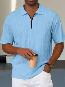 Dettaglio della polo azzurra con trama a maglia testurizzata e colletto con cerniera nera