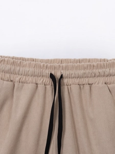 Close-up of khaki corduroy shorts with elastic waistband and black braided drawstrings