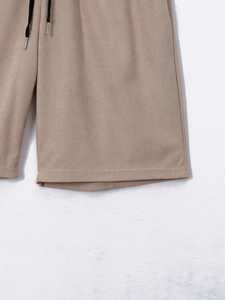 Detail of khaki corduroy shorts with elastic waistband and black drawstring tips