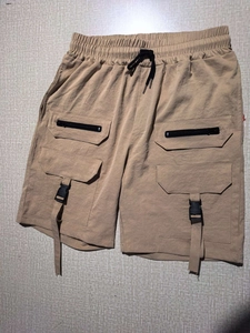 Detailed view of khaki cargo shorts with utility zipper pockets and buckle straps