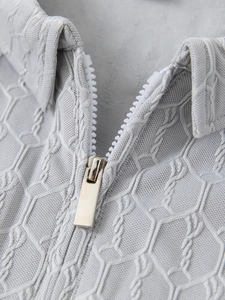 Macro du polo gris montrant le tissu jacquard hexagonal 3D et la fermeture éclair argent
