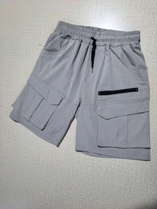 Detail of grey cargo shorts featuring elastic waistband, black drawstring and zipper pocket