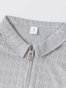 Détail du polo gris avec fermeture éclair en métal et texture de tissu jacquard hexagonal