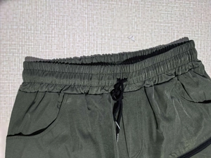 Detail of army green men's cargo shorts with elastic drawstring waist and metal aglets