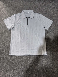 Dettaglio della polo da uomo grigio chiaro con trama jacquard geometrica e colletto a mezza zip