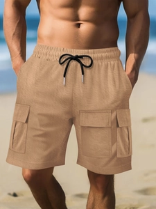 Detail of khaki cargo shorts with elastic drawstring waist and large utility pockets