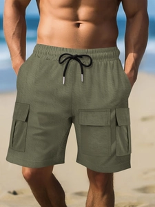 Detailed view of elastic waistband and drawstring on olive green cargo shorts