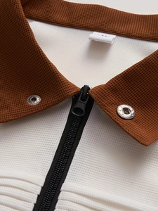 Detail shot of men's polo shirt featuring brown stand collar and white waffle knit fabric