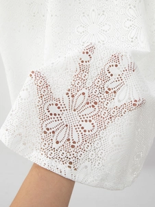 Vue détaillée du tissu en dentelle blanche avec motifs floraux et maille ajourée