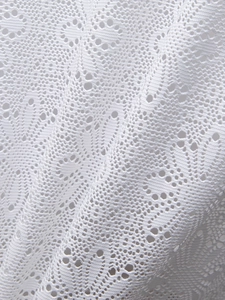 Détail du tissu en dentelle blanche avec motifs floraux sur une chemise à manches courtes