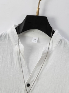 Close-up of white cotton short-sleeved shirt featuring a stand collar and 100% cotton texture