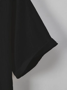 Detail shot of the black short sleeve cuff showing the folded hem and textured cotton fabric